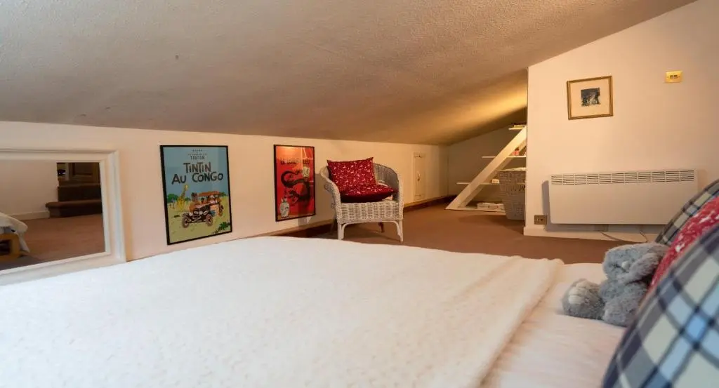 a bedroom with a white bed and a chair at Four Pines Lodge in Skye of Curr