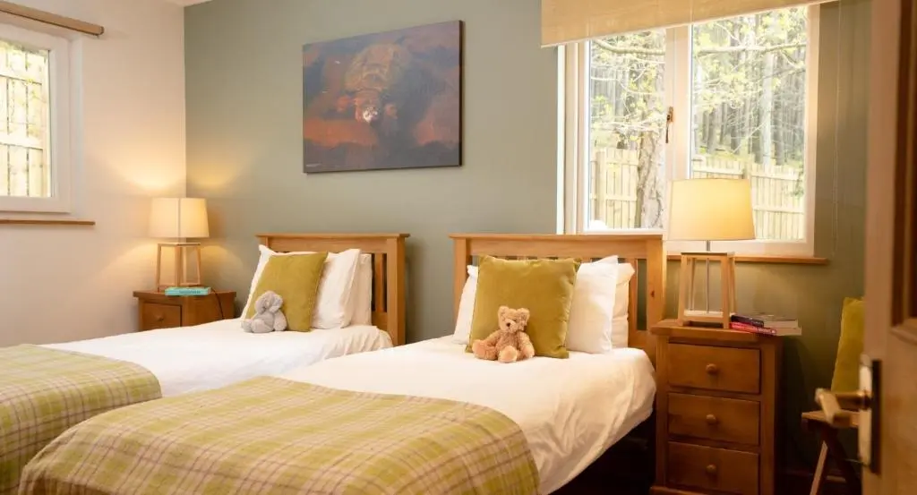 two beds in a room with two teddy bears on them at Salmon Run Lodge in Carrbridge