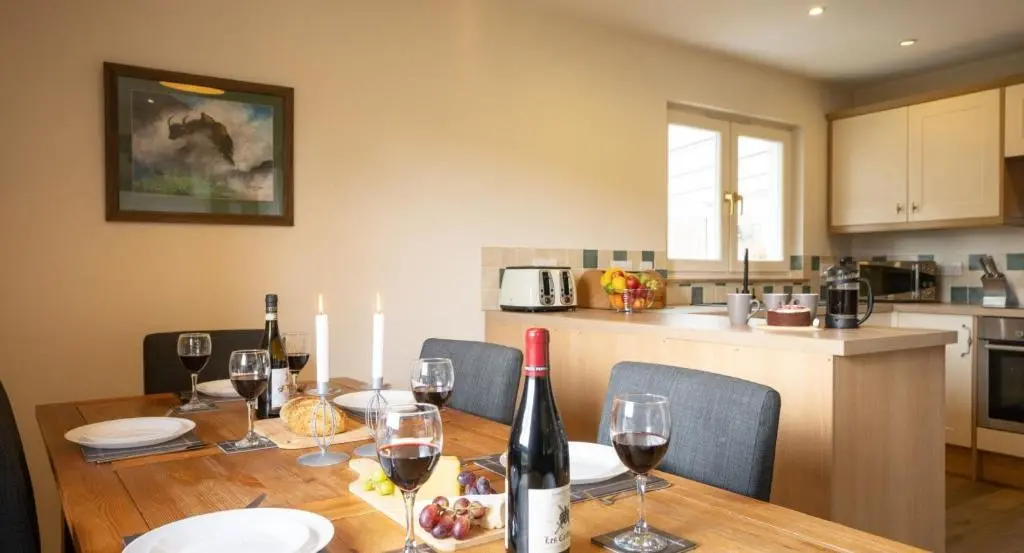 a dining room table with wine bottles and wine glasses at Salmon Run Lodge in Carrbridge