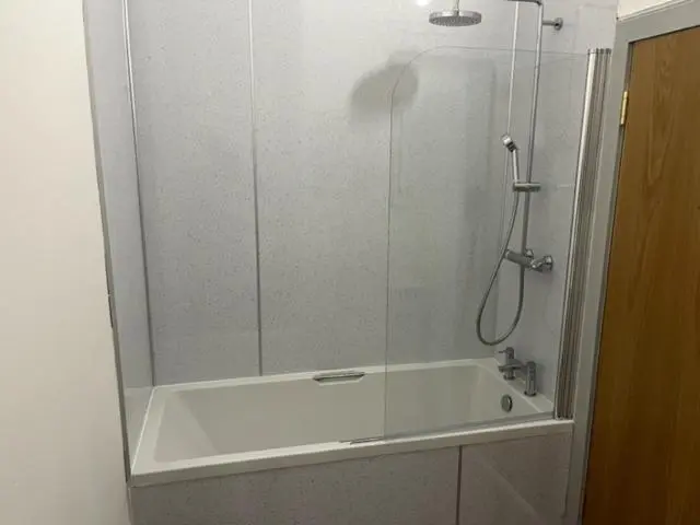 a shower with a glass door next to a tub at Duchally House in Nairn