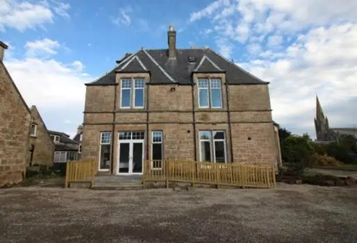 a large brick house with two benches in front of it at Duchally House in Nairn