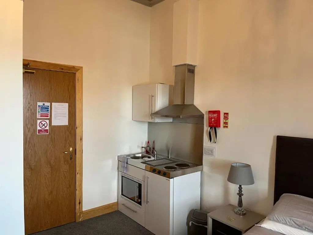 a small kitchen with a stove top oven next to a bed at Duchally House in Nairn