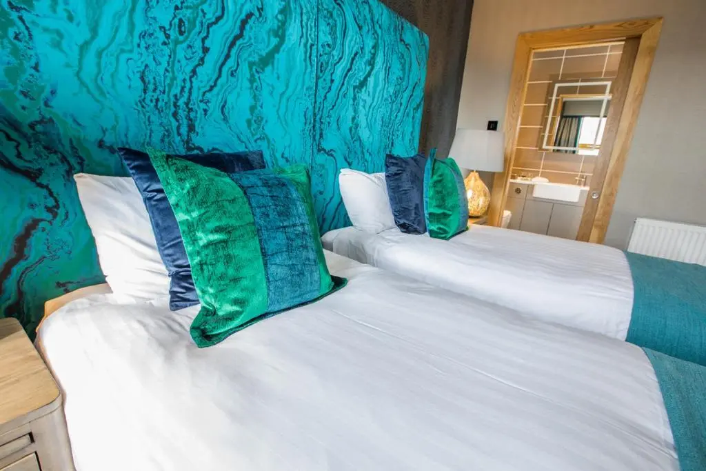 a bedroom with two white beds with green pillows at Heathmount Hotel in Inverness
