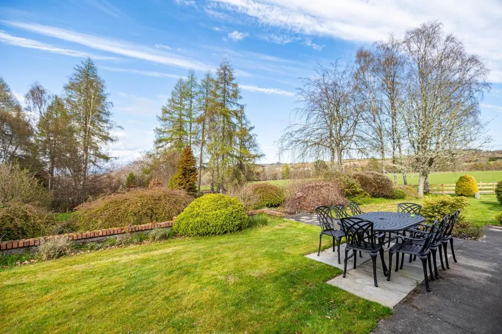 a table and chairs in the grass in a yard at Corrie House with Hot Tub in Belladrum