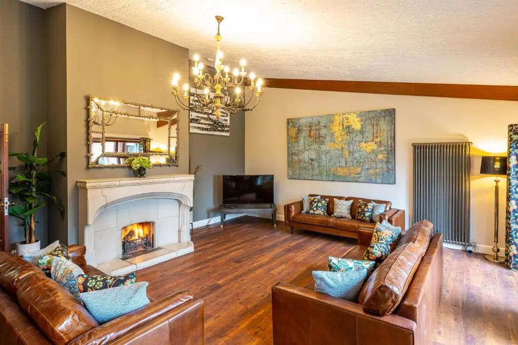 a living room with leather couches and a fireplace at Corrie House with Hot Tub in Belladrum
