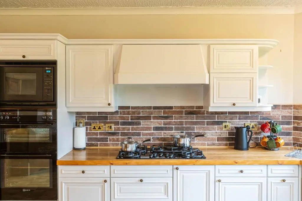 a kitchen with white cabinets and a stove top oven at Corrie House with Hot Tub in Belladrum
