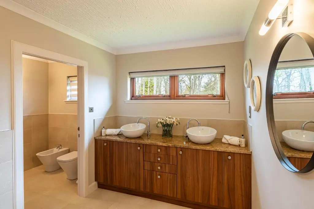 a bathroom with two sinks and a toilet at Corrie House with Hot Tub in Belladrum