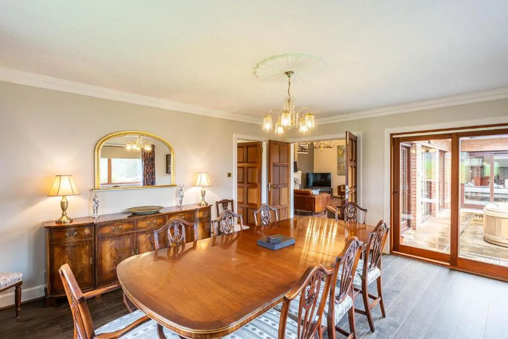 a dining room with a wooden table and chairs at Corrie House with Hot Tub in Belladrum