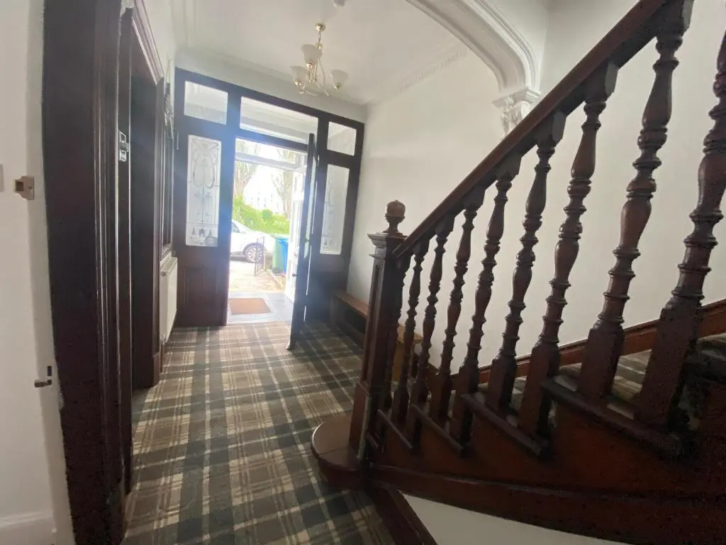 a hallway with a wooden stairway leading to a door at Stanford House in Inverness