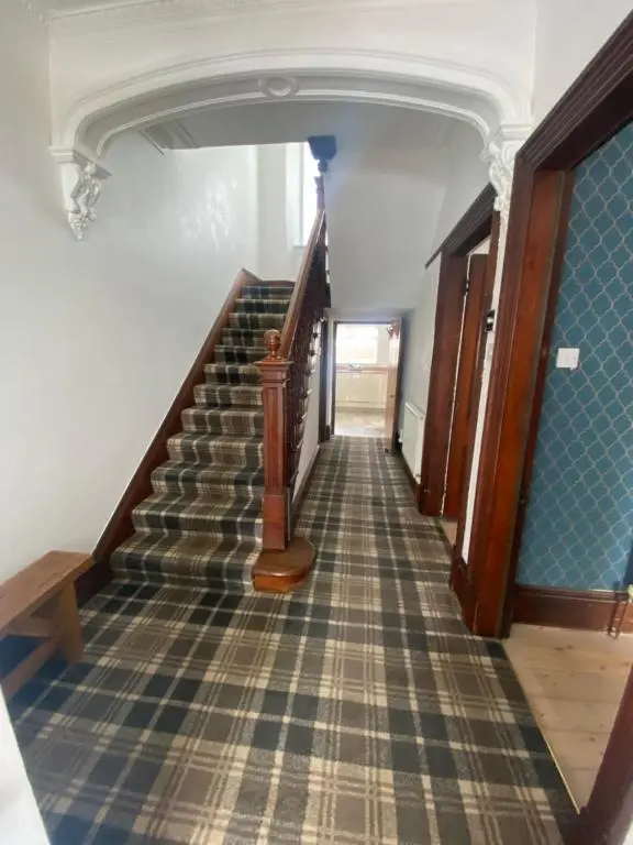 a hallway with a staircase with a checkerboard floor at Stanford House in Inverness