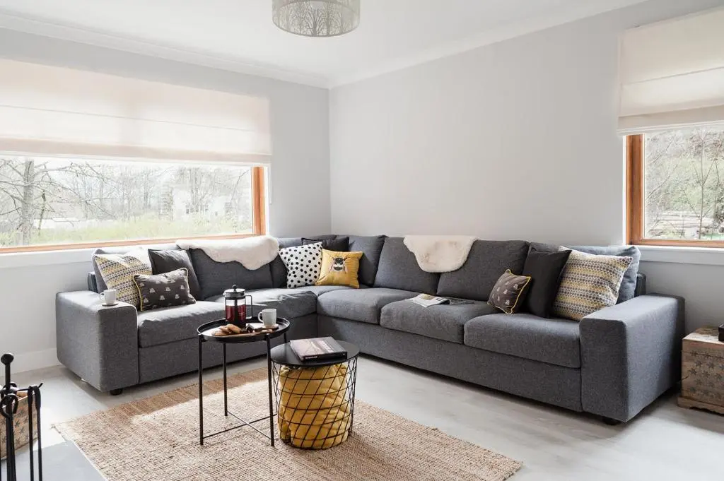 a living room with a gray couch with pillows at Gardeners Cottage - Seasgair Lodges in Aviemore