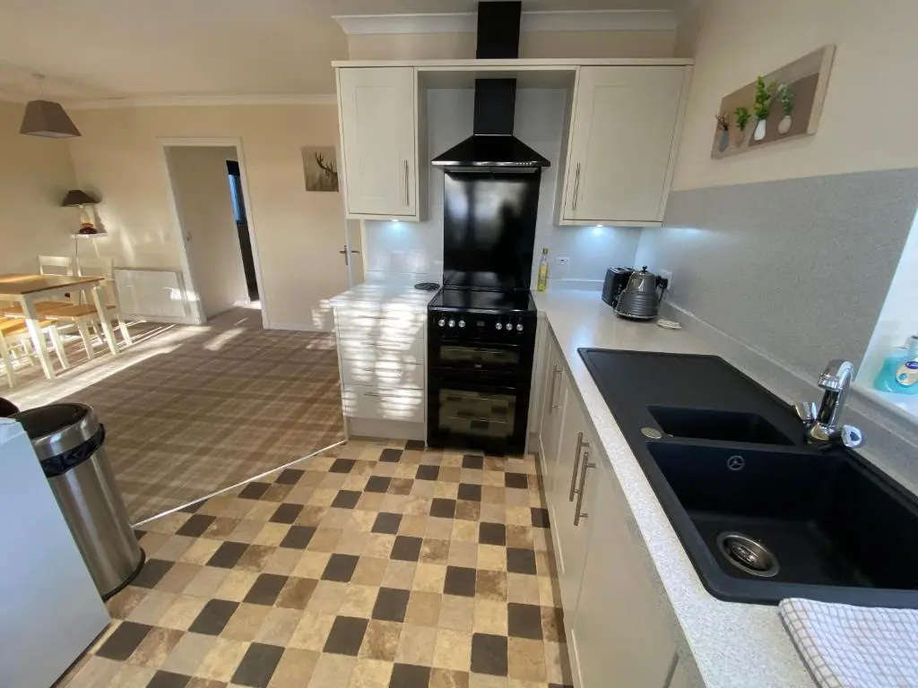 a kitchen with a black stove and a checkered floor at The Lodge at Woodend in Kemnay