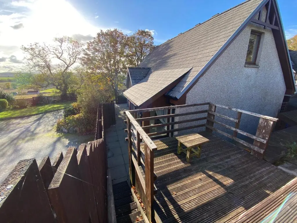 a house with a wooden deck with a bench on it at The Lodge at Woodend in Kemnay