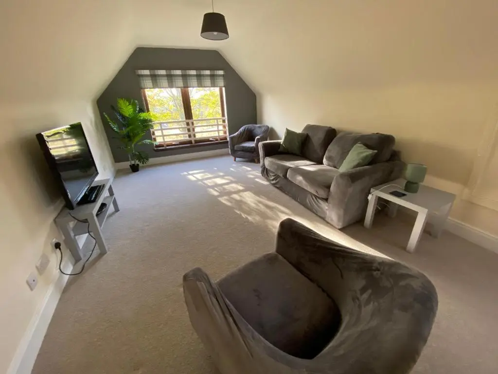 a living room with a couch and a tv at The Lodge at Woodend in Kemnay