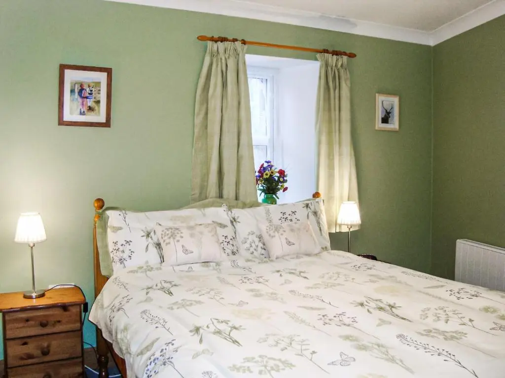 a bedroom with a bed with green walls and a window at The Bothy At Willowbank in Grantown on Spey