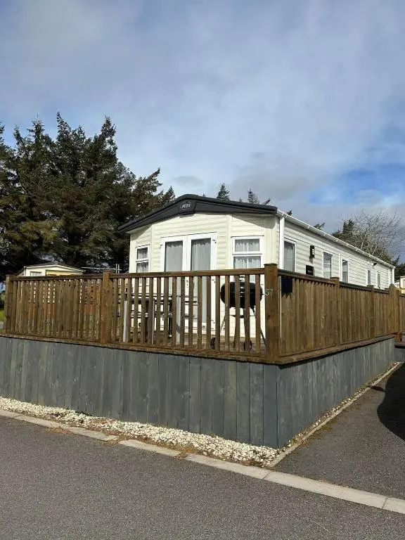a house behind a wooden fence with a house at Uisge Beatha in Dornoch