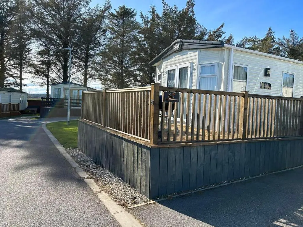 a house with a wooden fence next to a road at Uisge Beatha in Dornoch