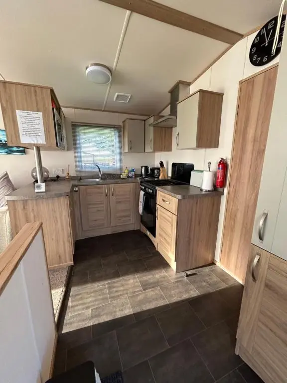 a kitchen with wooden cabinets and a stove top oven at Uisge Beatha in Dornoch