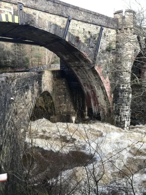 an old stone bridge over a river with snow at The Struan Inn Self Catering Lodge in Struan