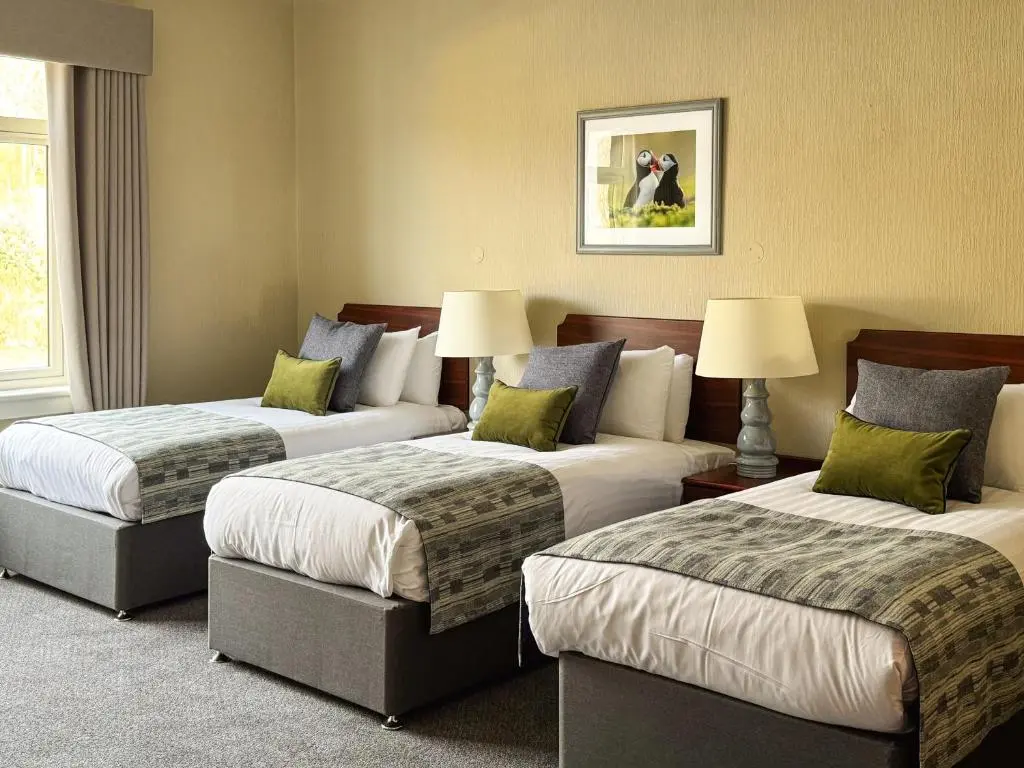 a hotel room with three beds with green pillows at The Royal Hotel in Ullapool