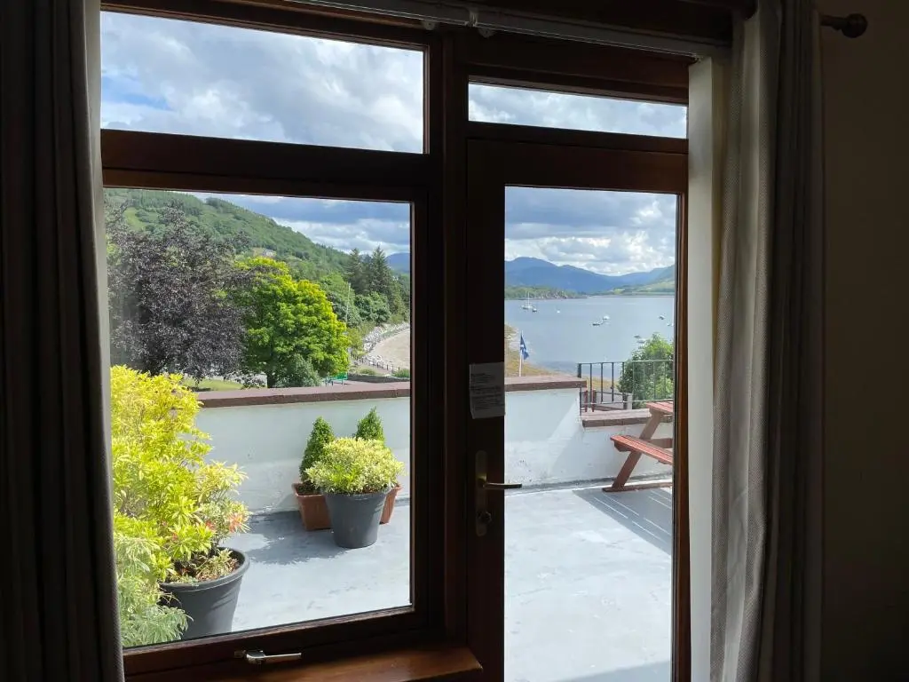 a door with a view of the water from a balcony at The Royal Hotel in Ullapool