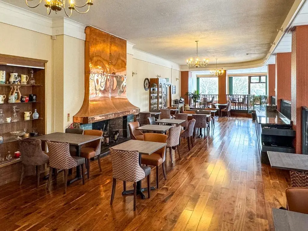 a restaurant with tables and chairs and a fireplace at The Royal Hotel in Ullapool