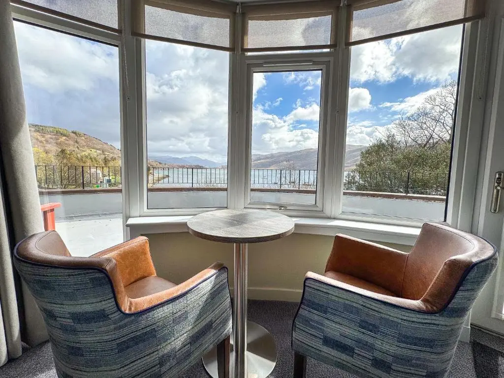 a room with two chairs and a table in front of a window at The Royal Hotel in Ullapool