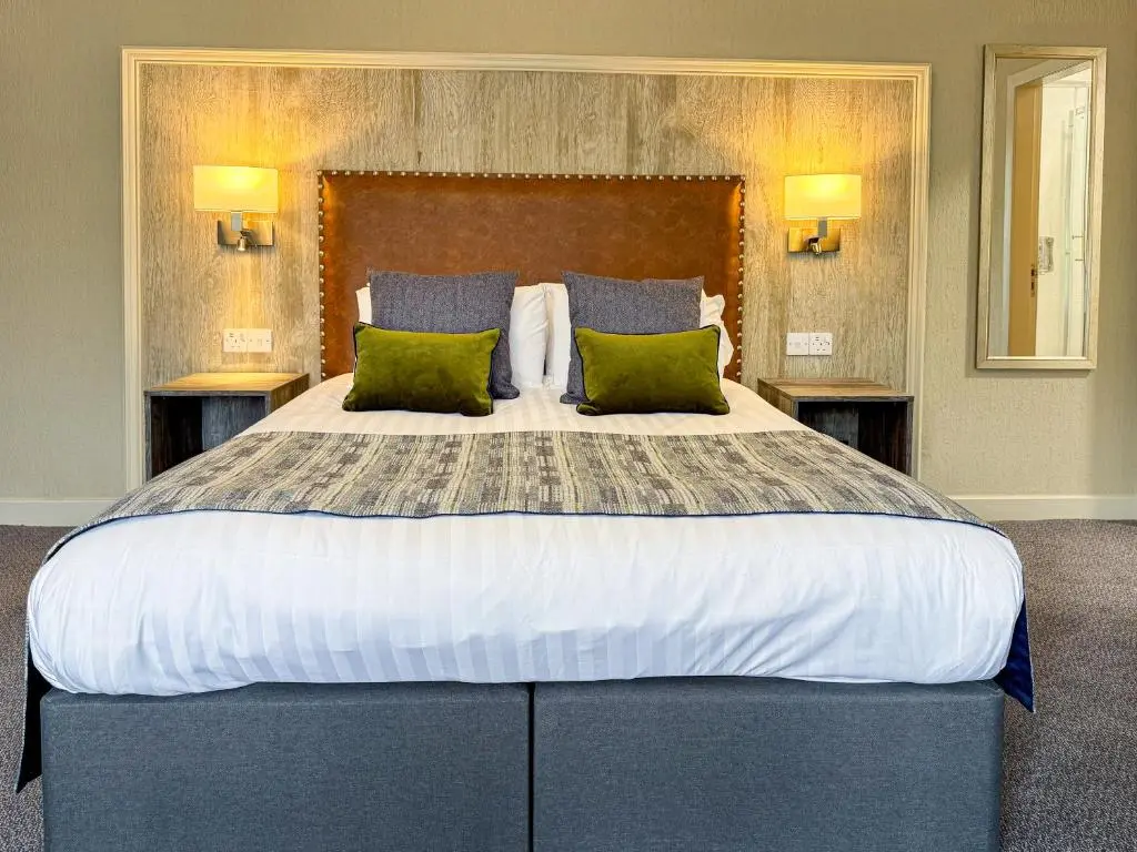 a bedroom with a large bed with green pillows at The Royal Hotel in Ullapool