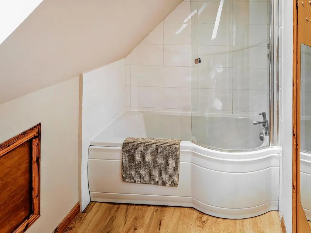 a white bath tub sitting in a bathroom at Rowan Cottage in Carrbridge