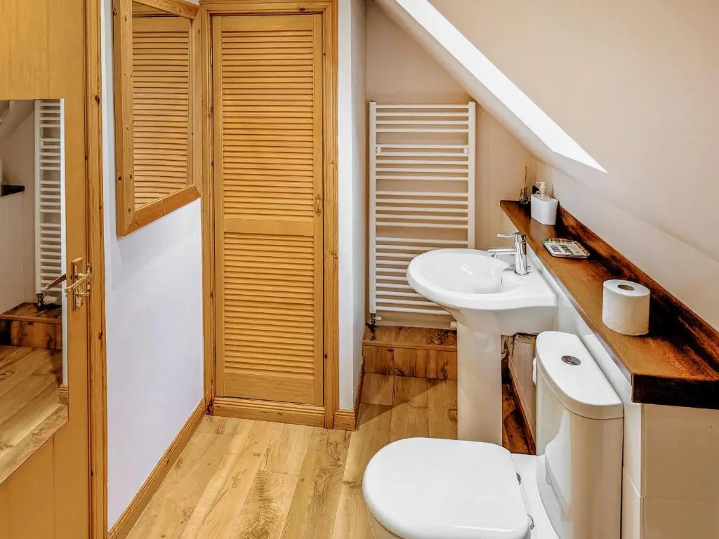 a bathroom with a white toilet and a sink at Rowan Cottage in Carrbridge