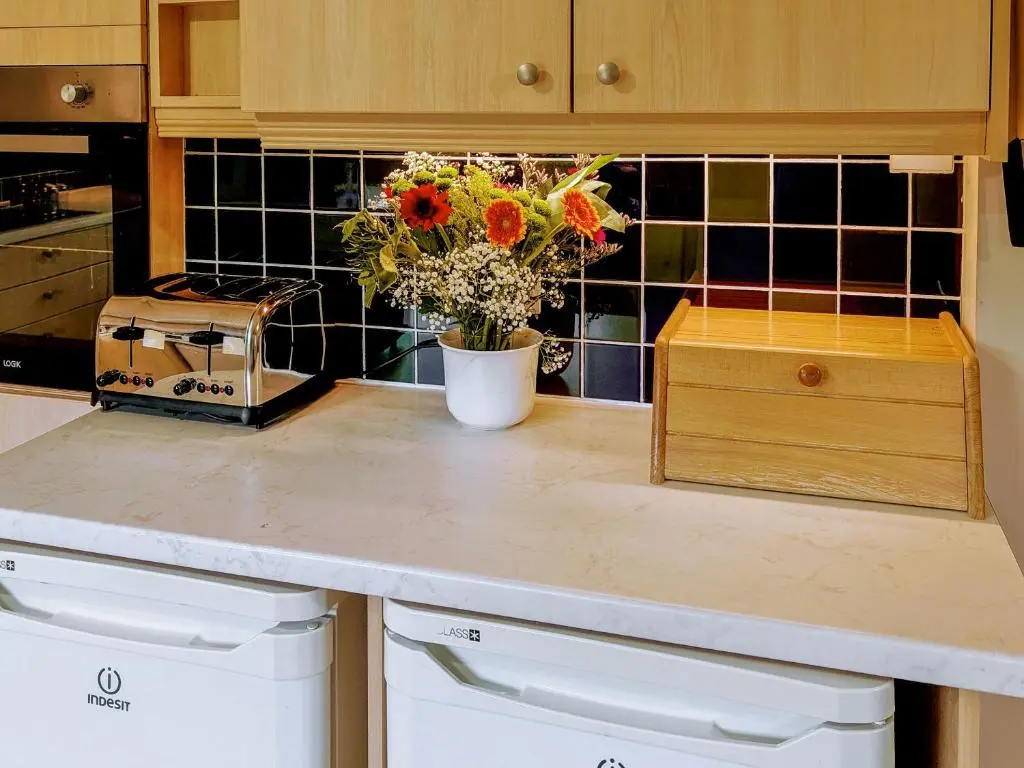 a kitchen counter with a vase of flowers on it at Rowan Cottage in Carrbridge