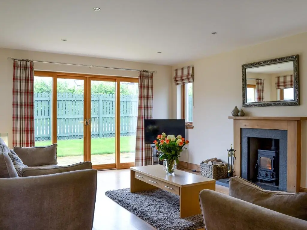 a living room with a fireplace and a mirror at 3 Allt Mor in Aviemore