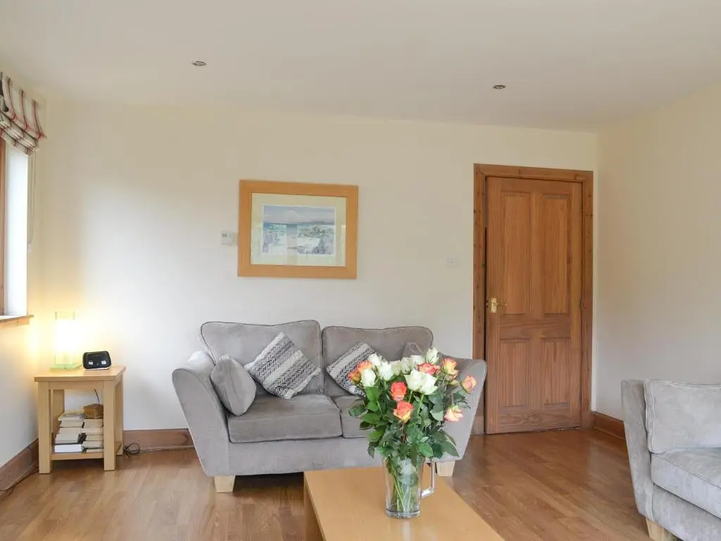a living room with a couch and a vase of flowers on a table at 3 Allt Mor in Aviemore