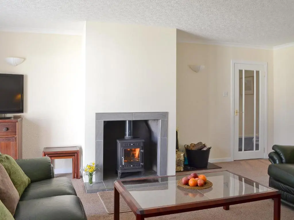 a living room with a fireplace and a coffee table at Tall Pines in Carrbridge