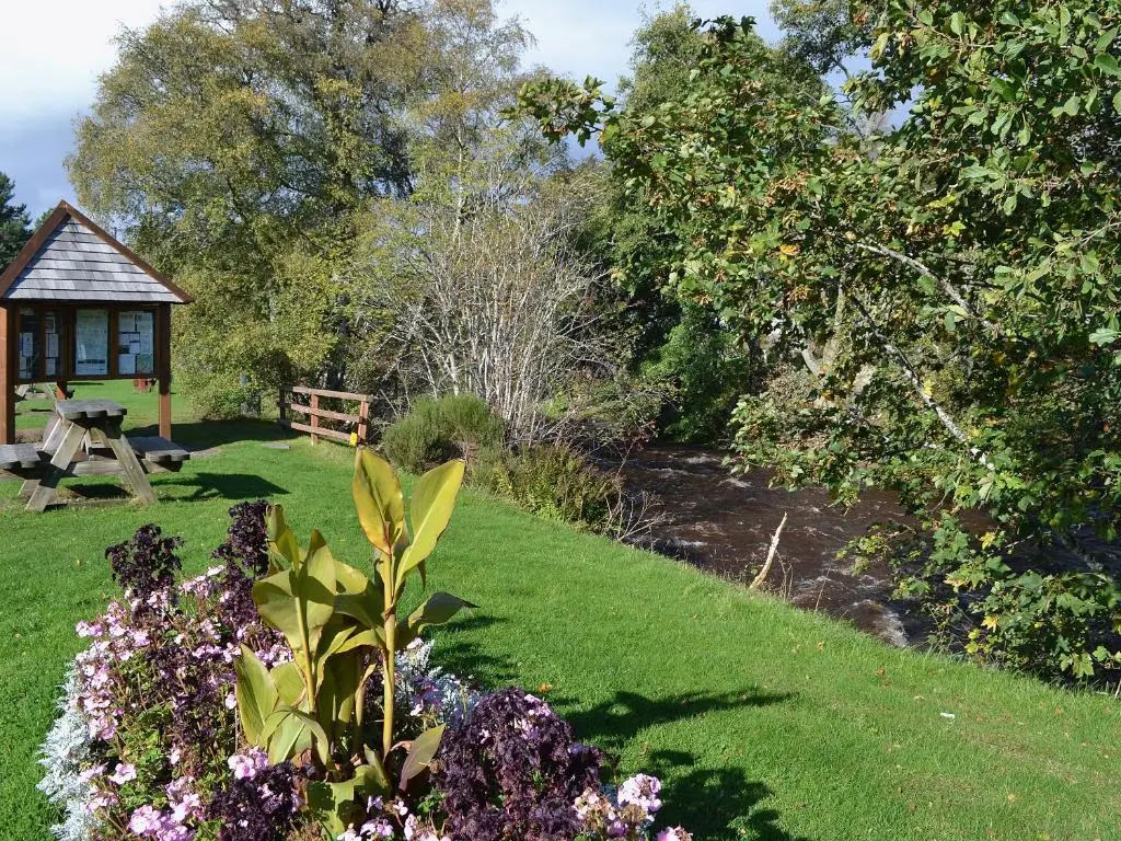 a garden with a bench and a table and flowers at Cotterton Beag in Nethy Bridge