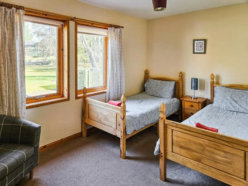 a bedroom with two beds and a window at Cotterton Beag in Nethy Bridge