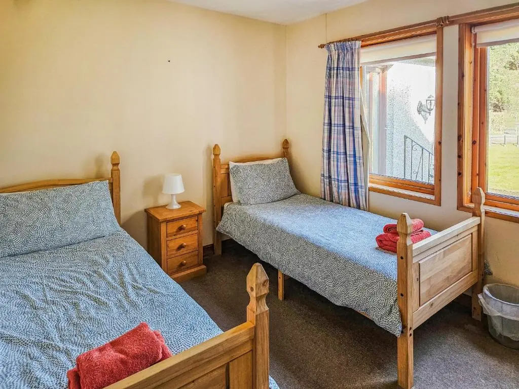 a bedroom with two beds and a window at Cotterton Beag in Nethy Bridge