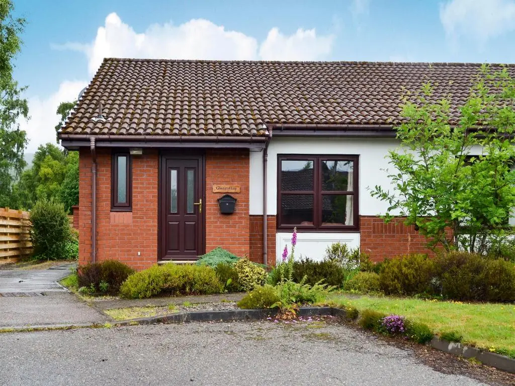 a red brick house with a black door at Glenrothay in Aviemore