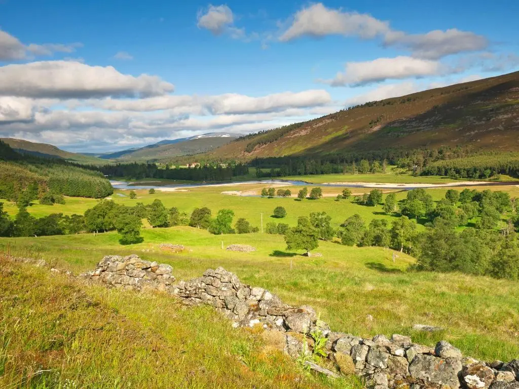 a green field with a stone wall on a hill at Glenrothay in Aviemore