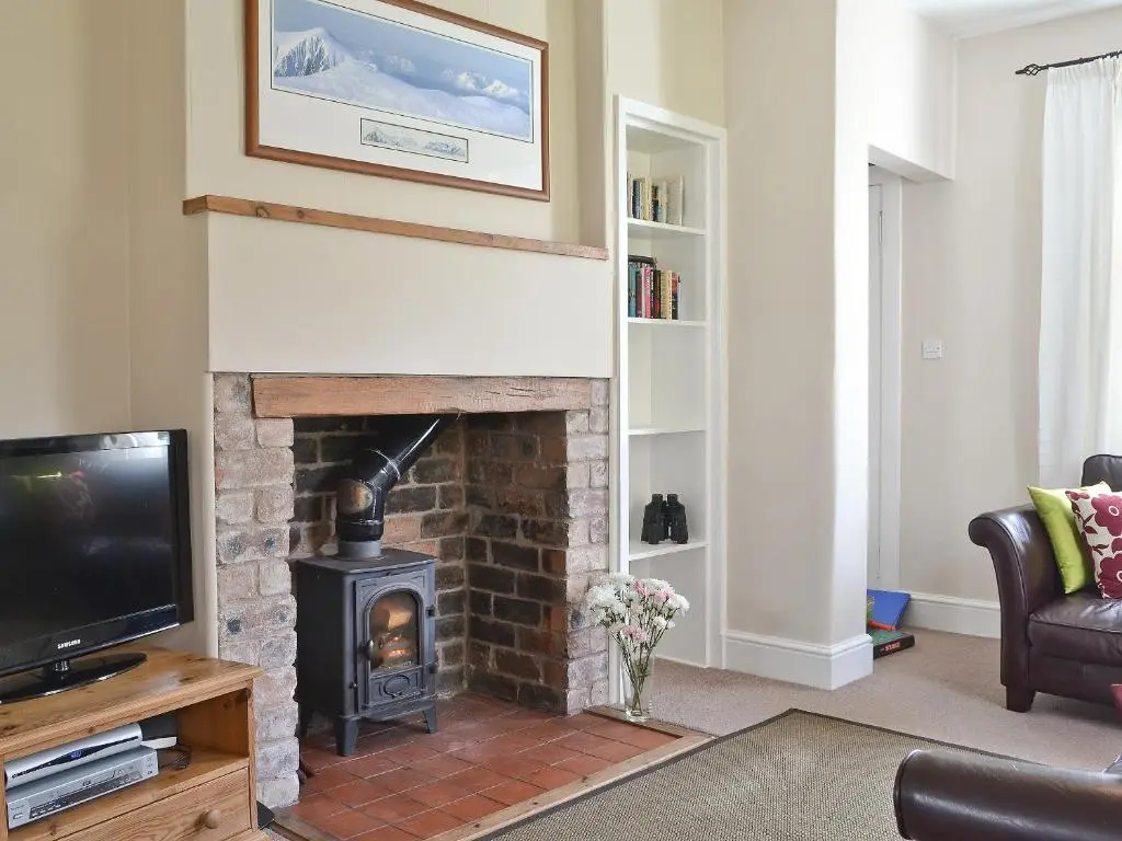 a living room with a fireplace and a tv at Caberfeidh in Skye of Curr