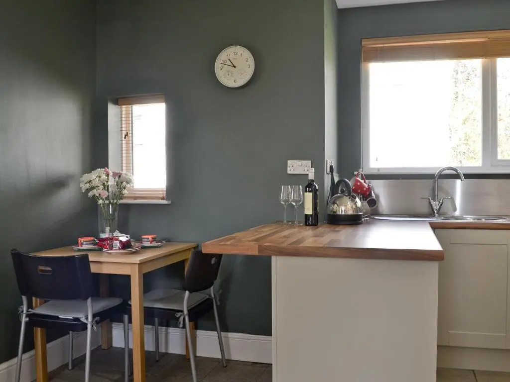 a kitchen with a table and a clock on the wall at Caberfeidh in Skye of Curr