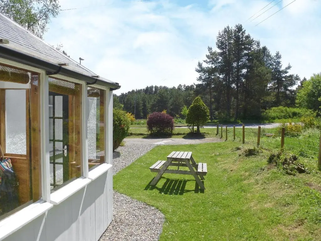 a picnic table in the grass next to a house at Caberfeidh in Skye of Curr