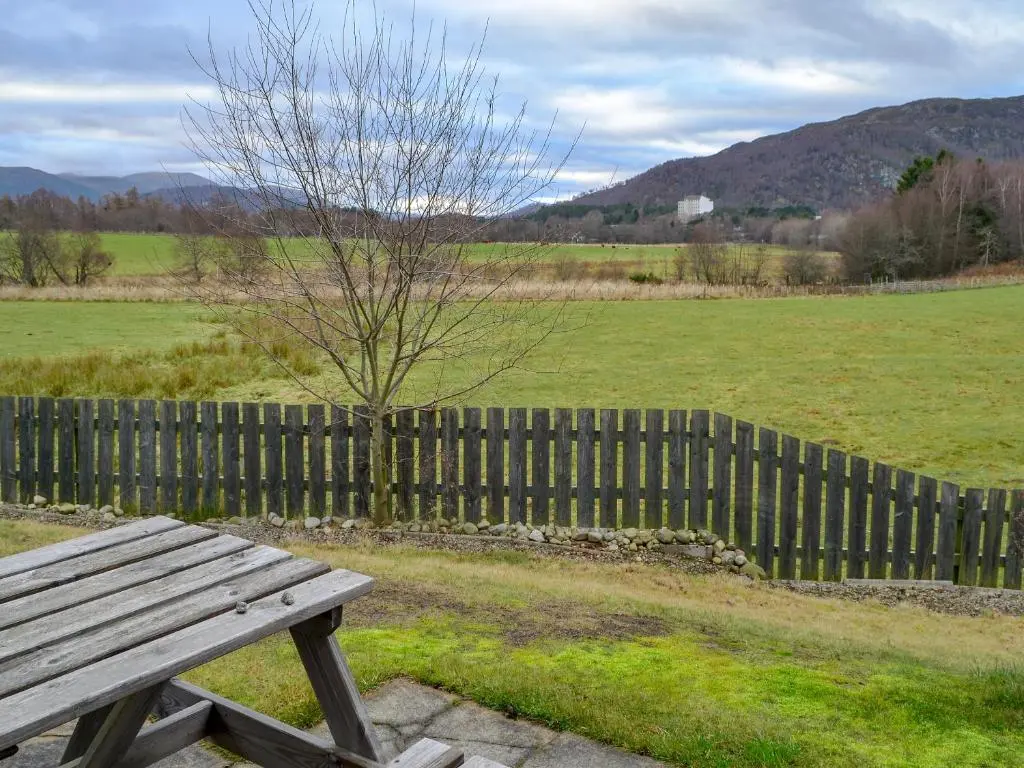 a wooden bench sitting in front of a fence at Birch Tree Cottage in Aviemore