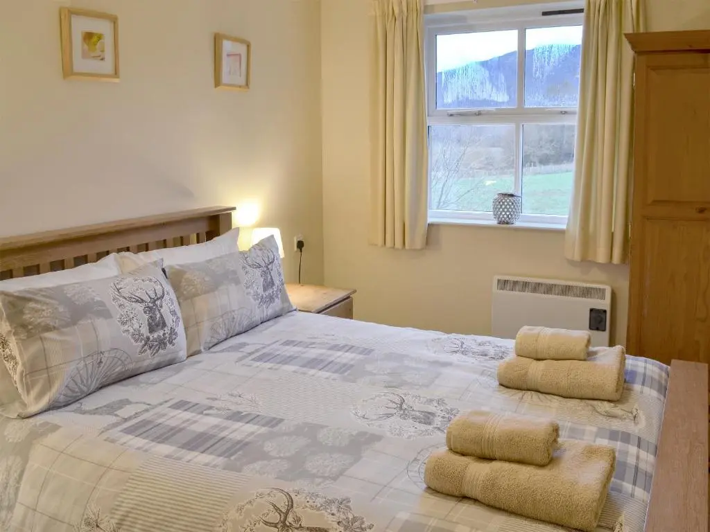 a bedroom with a bed with two towels on it at Birch Tree Cottage in Aviemore
