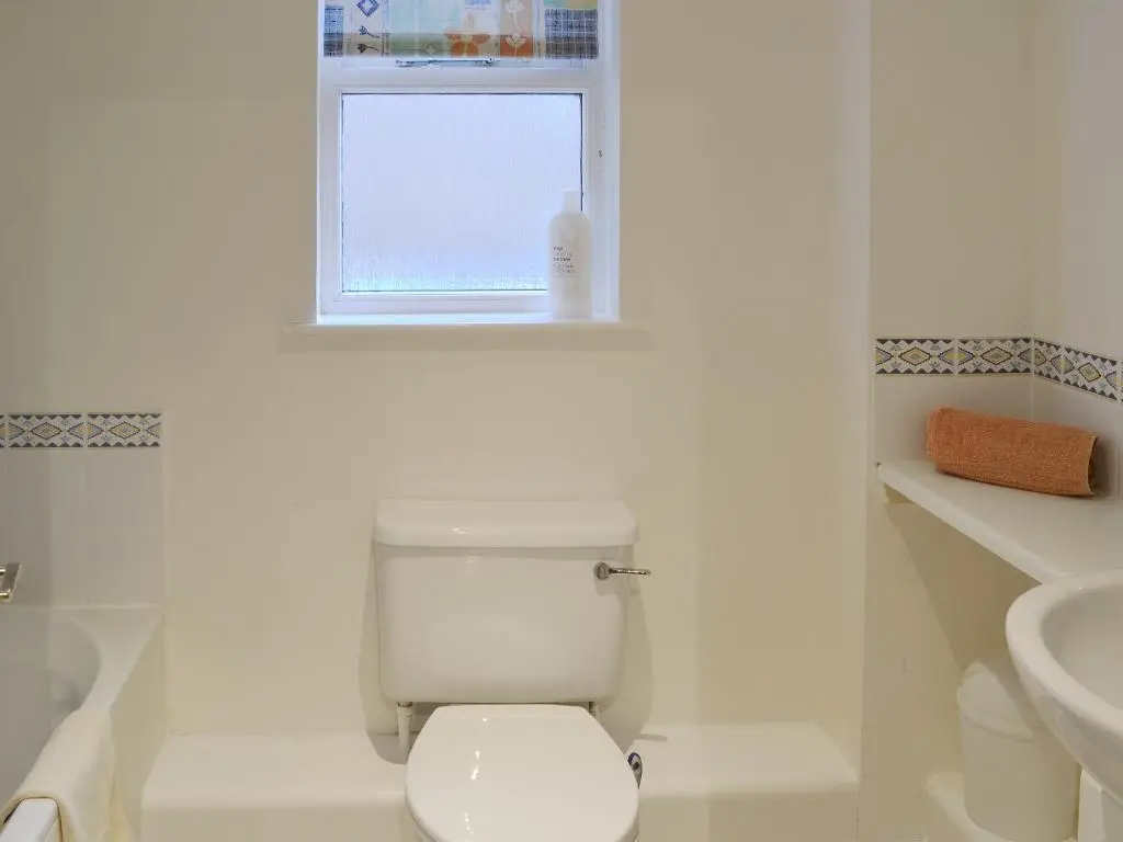 a white bathroom with a toilet and a sink at Birch Tree Cottage in Aviemore