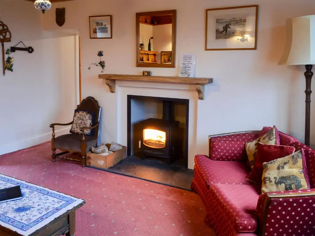 a living room with a fireplace and a red couch at Culcharry Cottage in Cawdor