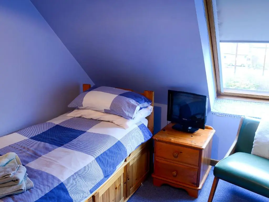 a bedroom with a bed and a television on a dresser at Culcharry Cottage in Cawdor