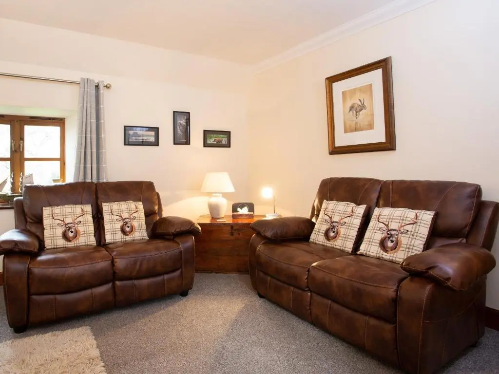 two leather chairs and a table in a living room at Craigellachie Cottage in Croy