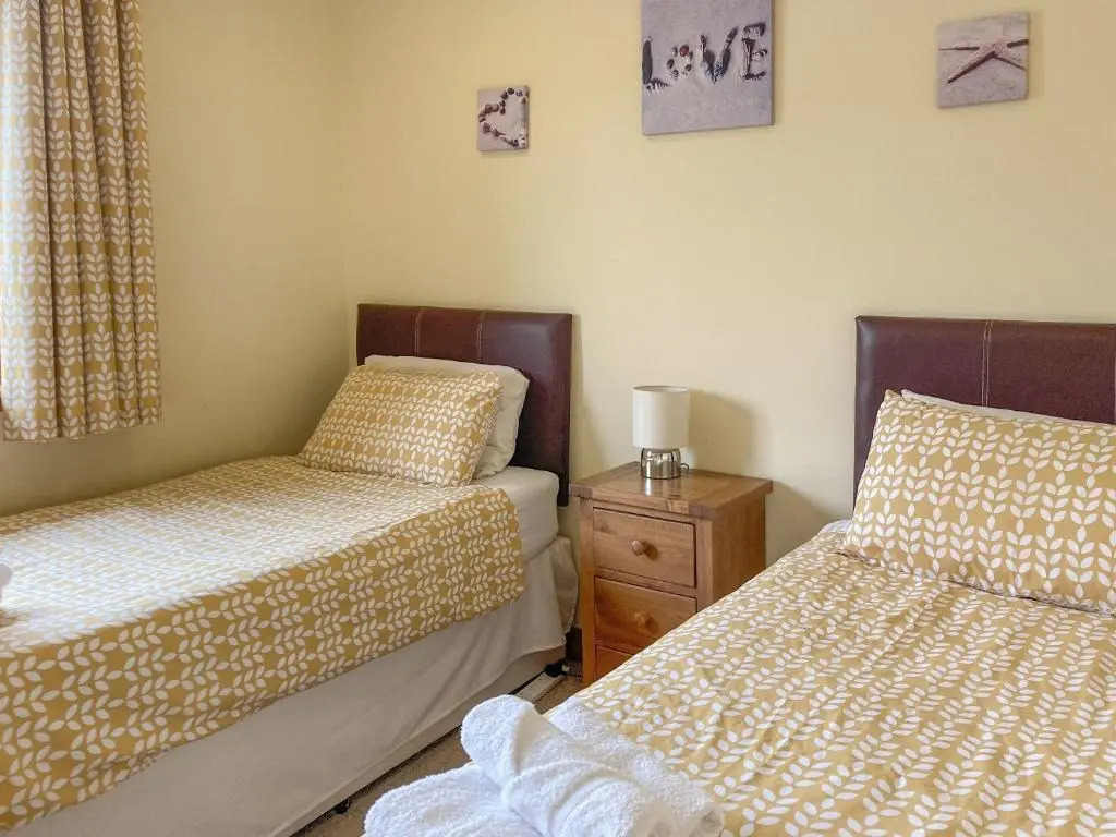 a bedroom with two beds and a dresser with a night stand at Sandy Beach in Nairn