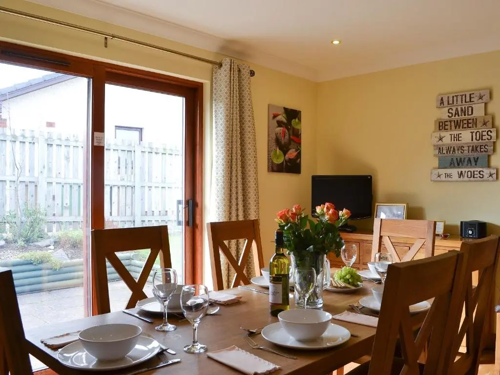 a dining room table with chairs and a large window at Sandy Beach in Nairn